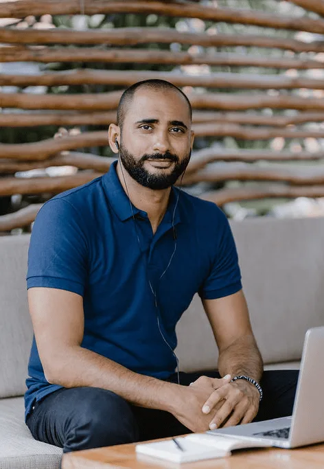 Porträtfoto von Jose Flores, männlich, dunkles Haar, dunkelblaues Poloshirt, sitzt mit Laptop