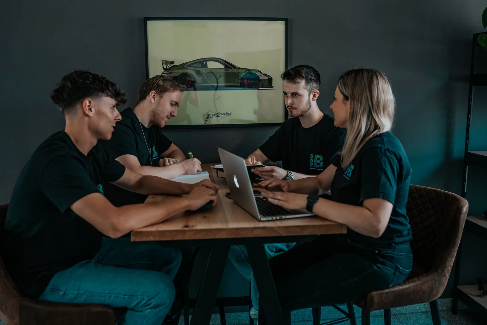 Einsteigerkurs Social Media & Reels von Vanessa Glaser 19 Vier Mitarbeiter sitzen um einen Tisch mit Laptop und besprechen ein Projekt