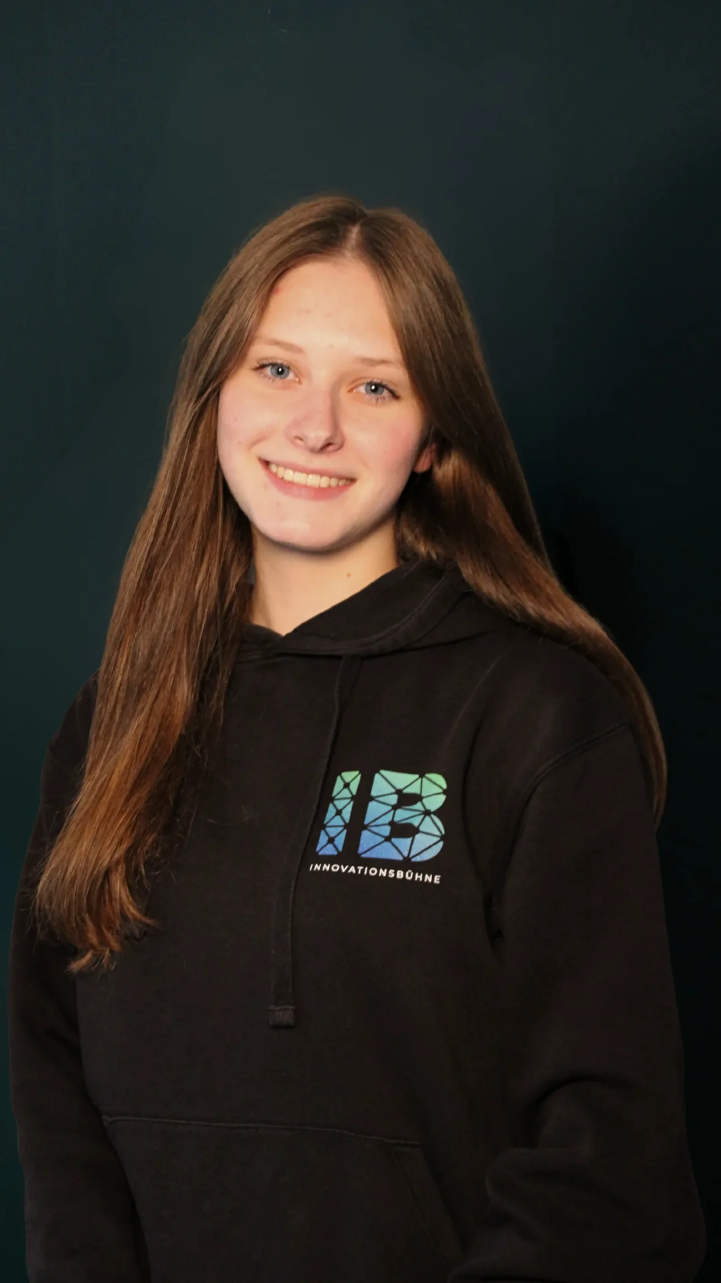 Einsteigerkurs Social Media & Reels von Vanessa Glaser 23 Porträt einer lächelnden jungen Frau mit braunem Haar in schwarzem Hoodie mit Innovationsbühne-Logo