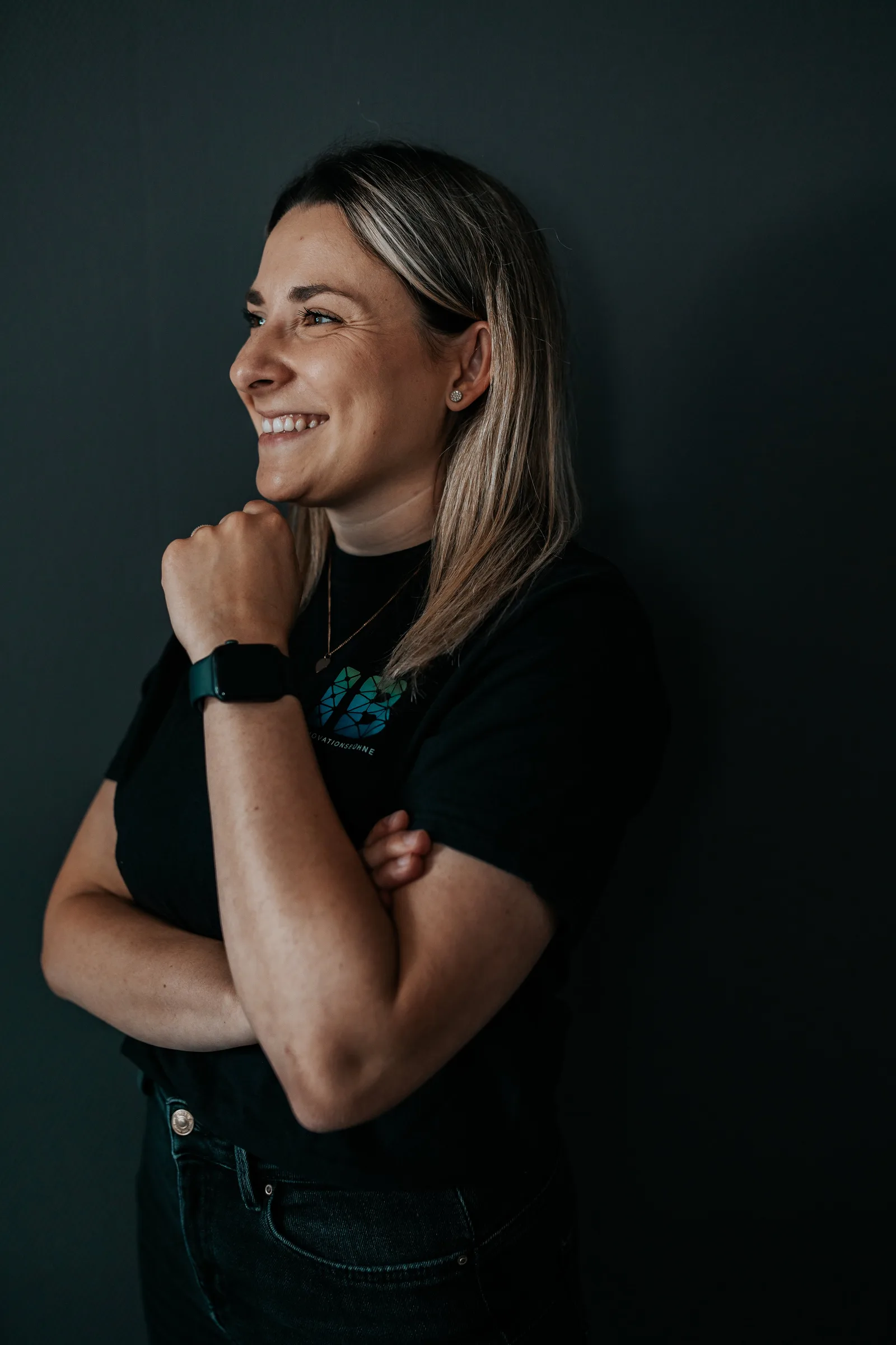 Einsteigerkurs Social Media & Reels von Vanessa Glaser 24 Profilporträt einer lächelnden Frau in schwarzem Innovationsbühne-Shirt vor dunkelgrünem Hintergrund