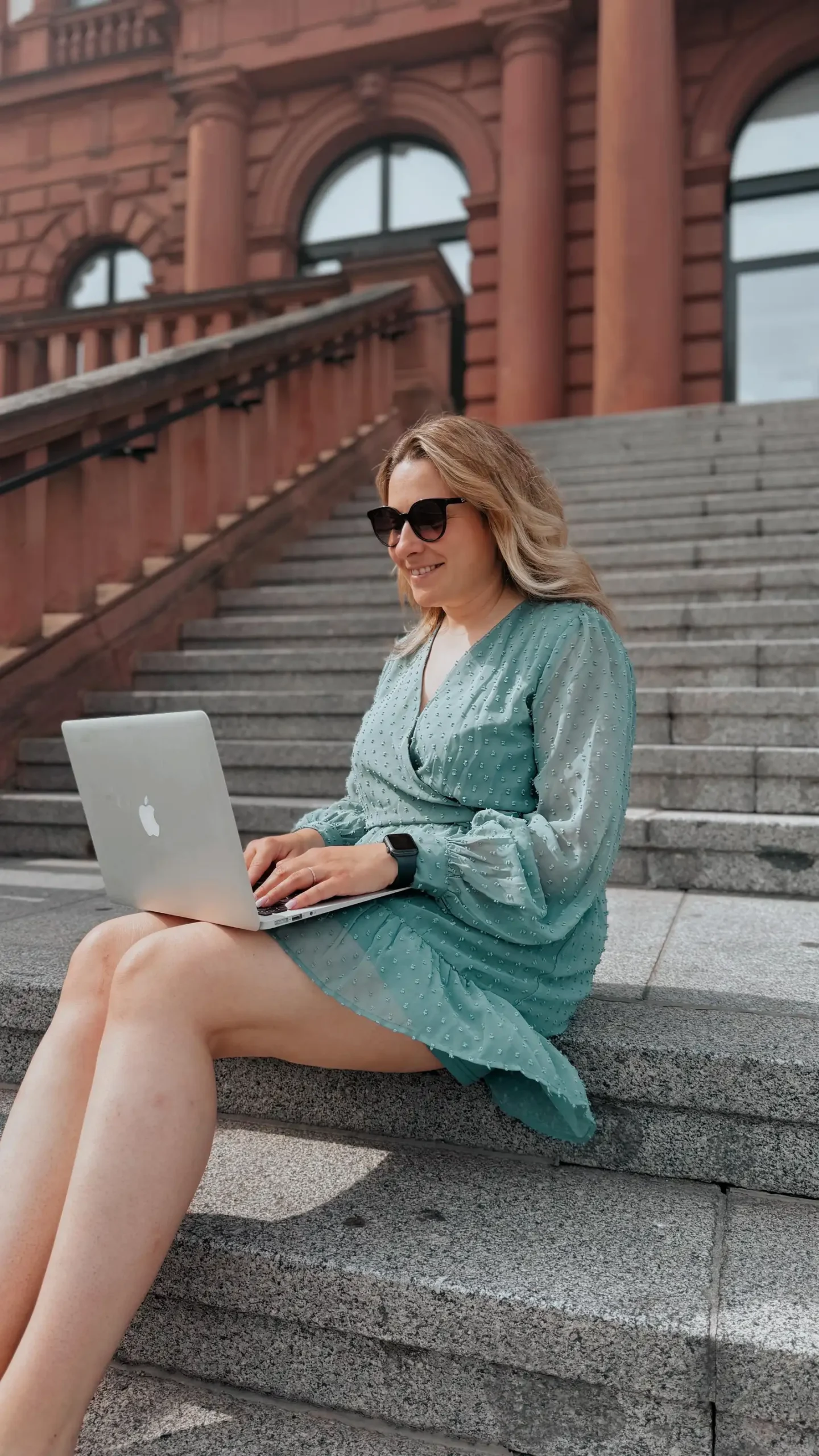 Einsteigerkurs Social Media & Reels von Vanessa Glaser 1 Frau mit Laptop auf Treppen vor Backsteingebäude, Lifestyle-Fotografie des Kurses