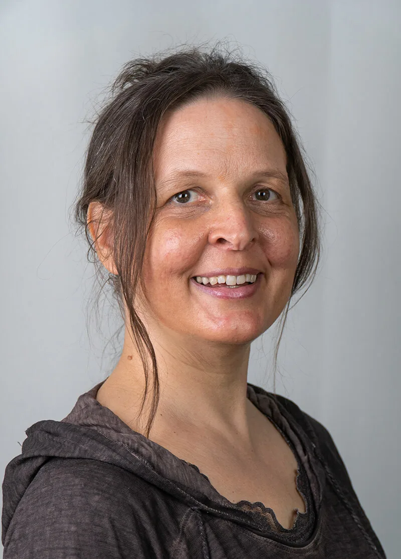 Porträt von Antje Tittelmeier, Autorin des Schlaf-Kurses, lächelnd vor grauem Hintergrund
