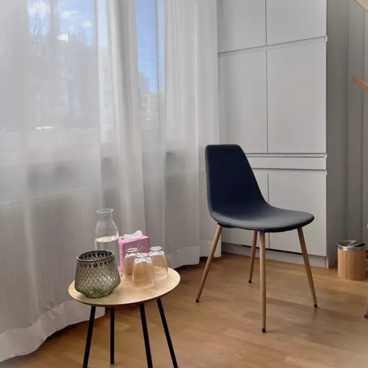 Minimalistische Praxis-Raum mit schwarzem Stuhl, Tisch, helle Gardinen