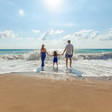 Familie mit zwei Kindern am Strand im Meer, helles Tageslicht