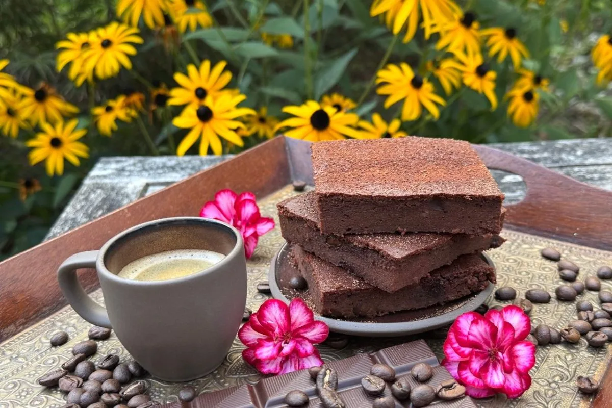 Gestapelte Low Carb Schoko Brownies mit Mokka, Kaffee und Blüten auf Holzbrett