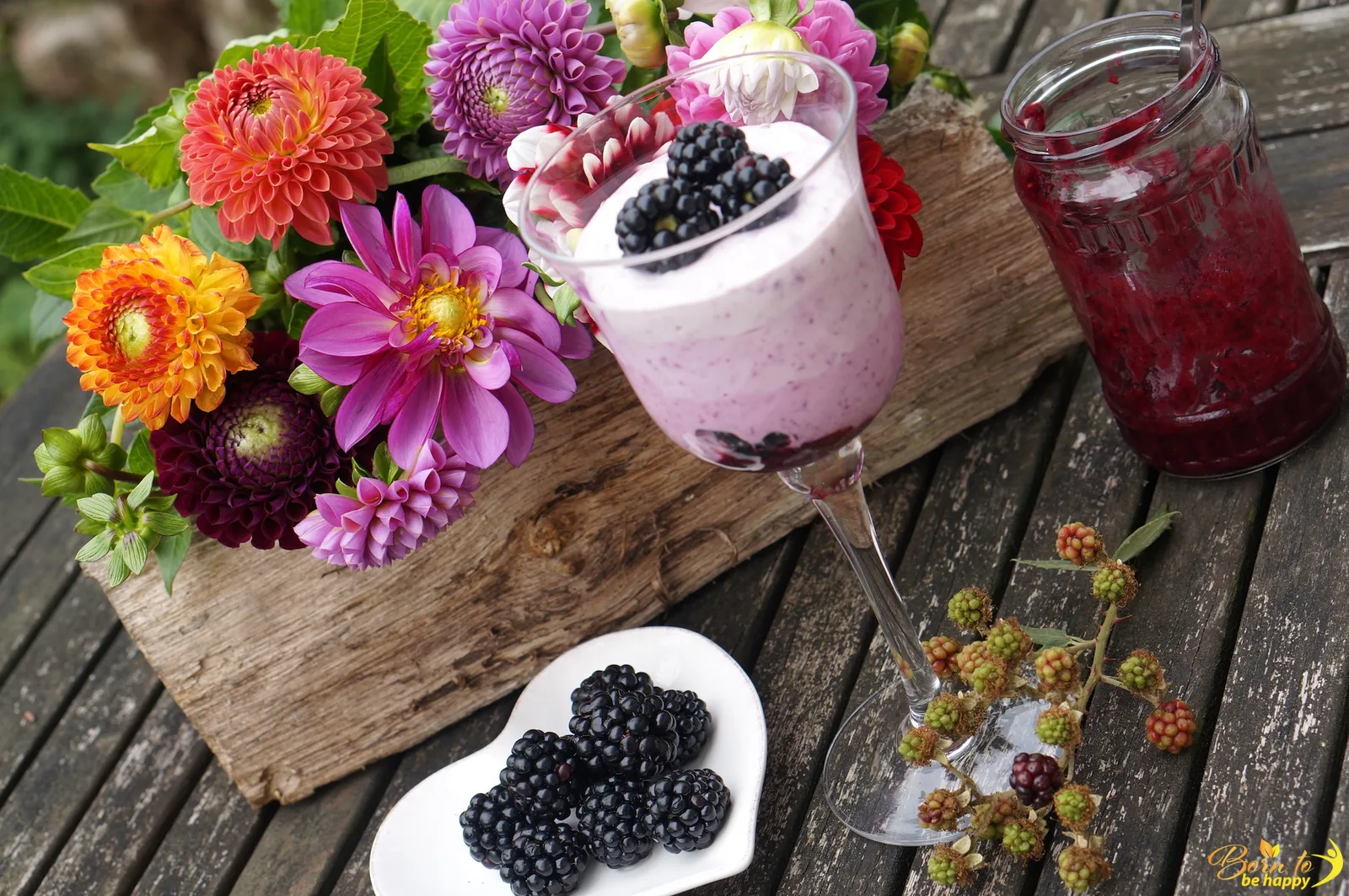 Blackberry Mascarpone Cream Dessert im Glas mit Brombeeren, Blüten und Beeren auf Holz
