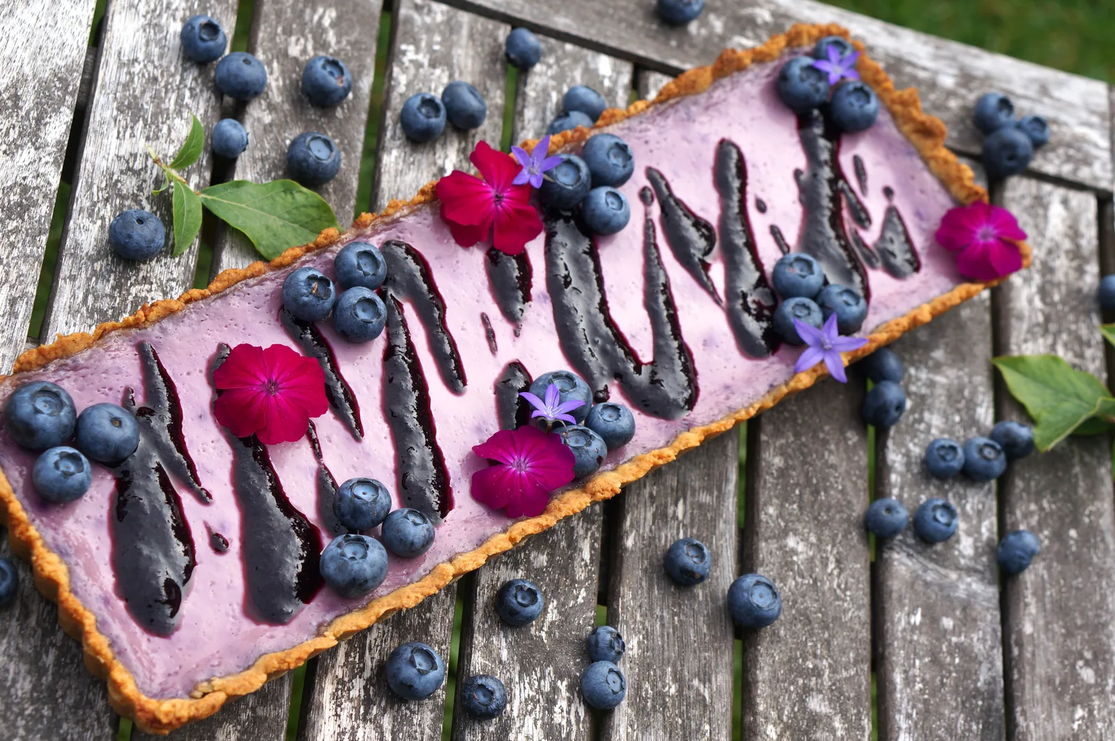 Blaubeer-Tarte Low Carb mit rosa Creme, Blaubeeren und Schokoladenstreifen auf Holz
