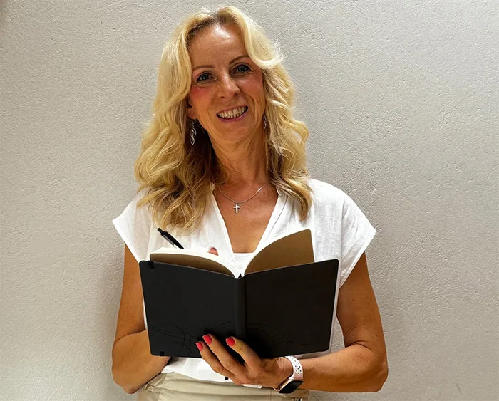Porträt Stella Cornelius-Koch mit offenem Buch in weißem Top