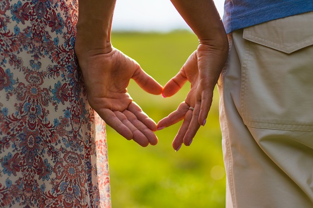 Zwei Personen bilden mit ihren Händen ein Herz in der Natur mit grünem Hintergrund