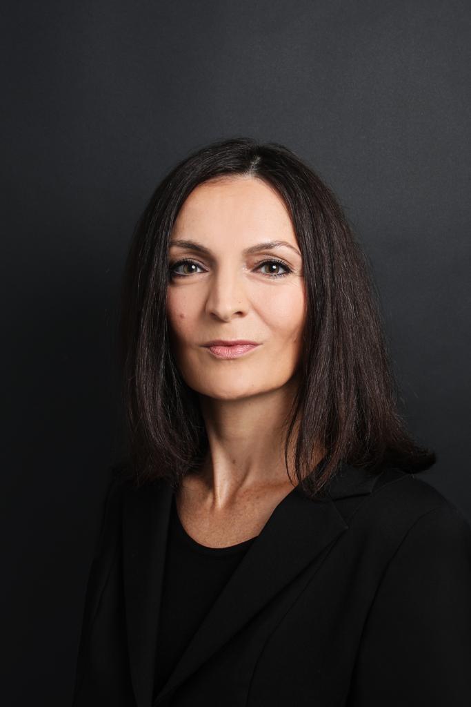 Porträt einer Frau mit dunklem Haar vor schwarzem Hintergrund, professionelle Headshot