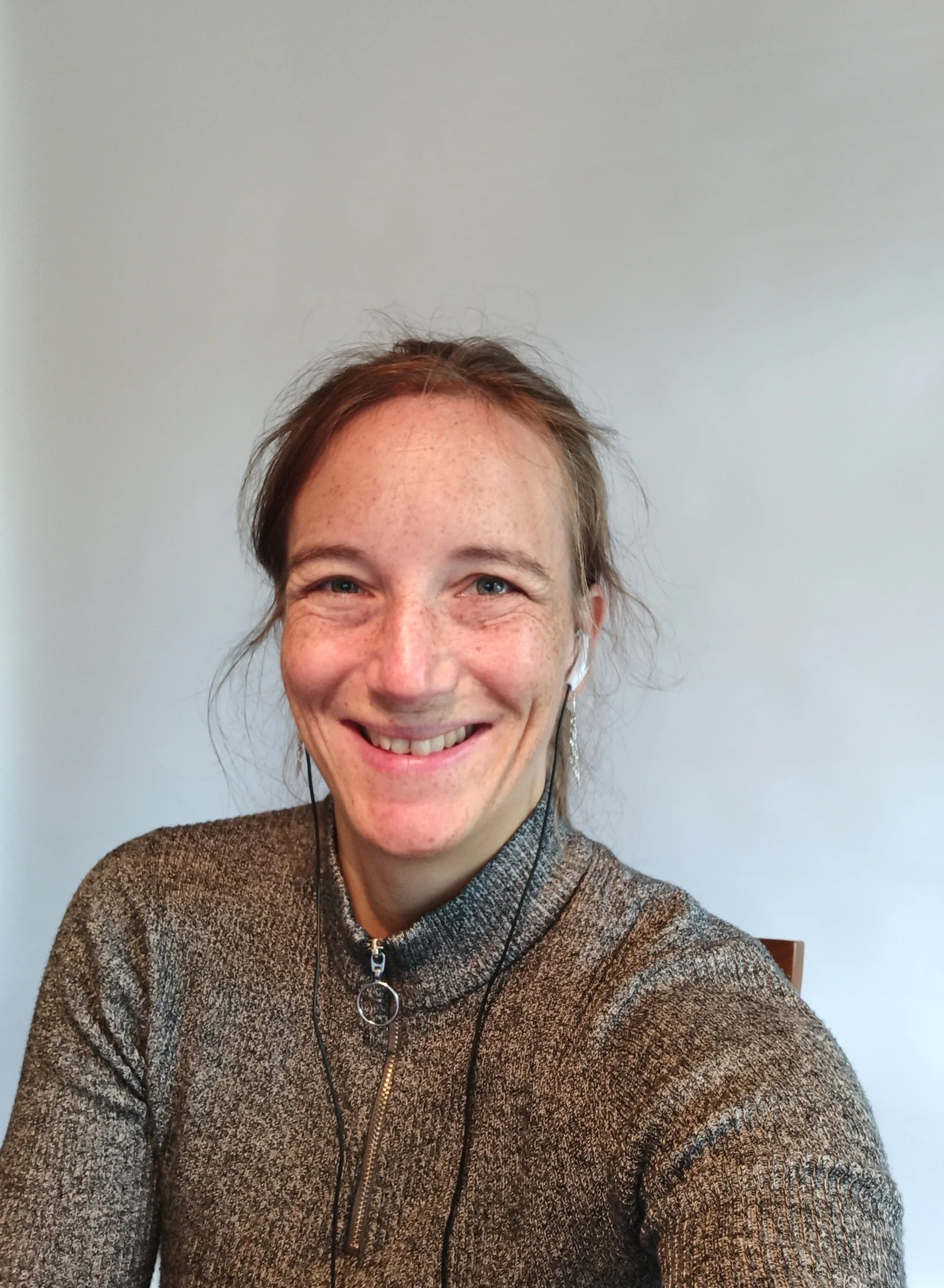 Porträt von Anke Weber, lächelnd, braune Haare, braune Strickjacke, silberne Halskette