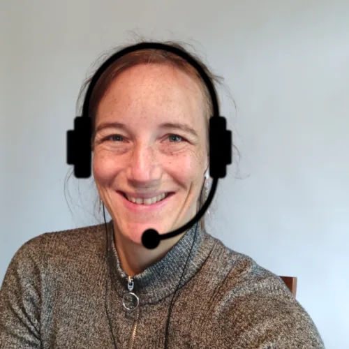 Frau mit Kopfhörer und Mikrofon lächelt in die Kamera, Online-Coaching-Setup