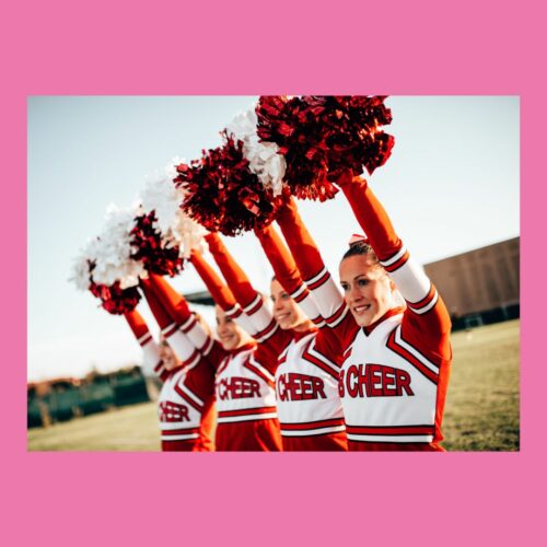 Cheerleaderinnen in roter und weißer Uniform mit Pompons auf grünem Feld