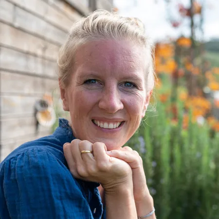 Expedition Familie – Videokurs für werdende Eltern 22 Lisa Hobelsberger, Frau mit rötlich-blonden Haaren in weißem Shirt vor grünem unscharfem Hintergrund