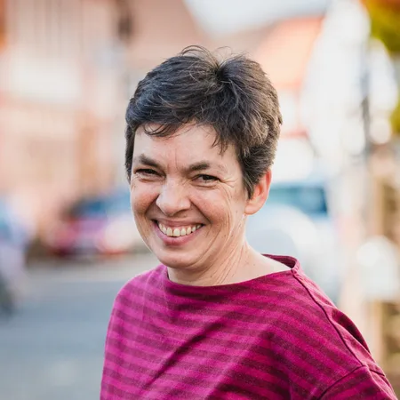 Expedition Familie – Videokurs für werdende Eltern 30 Porträt von Ulrike Gillert in magentafarbener Bluse, lächelnd in städtischem Umfeld