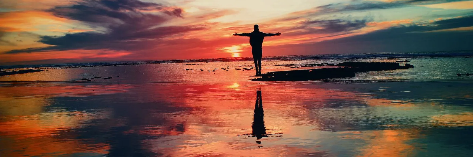 Externenprüfung Betreuungsrecht von Soteris Sozialakademie 2 Silhouette einer Person mit ausgebreiteten Armen bei Sonnenuntergang am Strand mit Spiegelung