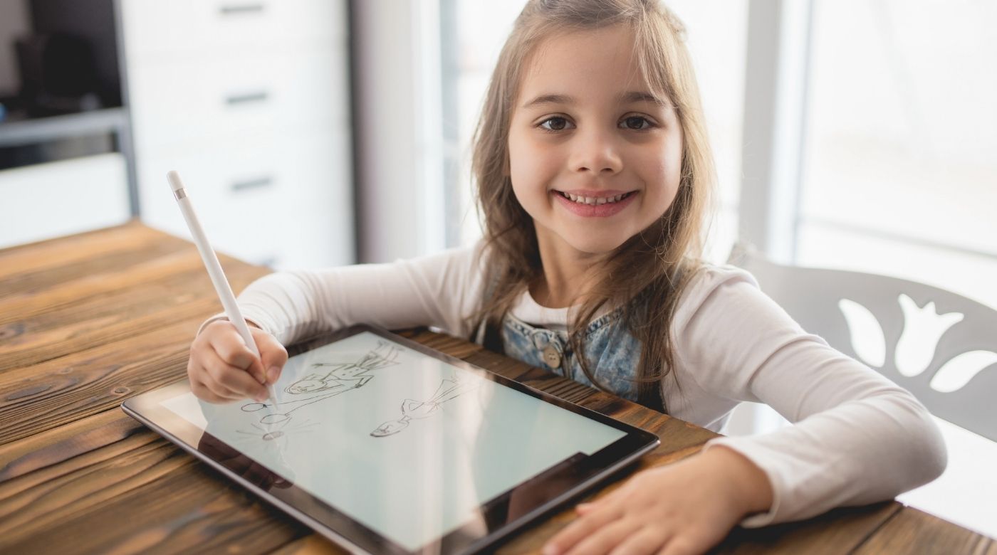 Mädchen zeichnet mit Stift auf einem Tablet-Display an einem Holztisch