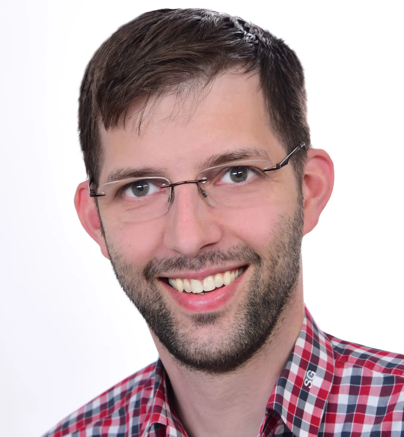 Porträt eines lächelnden Mannes mit Brille in kariertem Hemd vor weißem Hintergrund