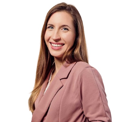 Porträt einer Frau mit braunen Haaren und Rosa-Blazer, lächelnd vor weißem Hintergrund