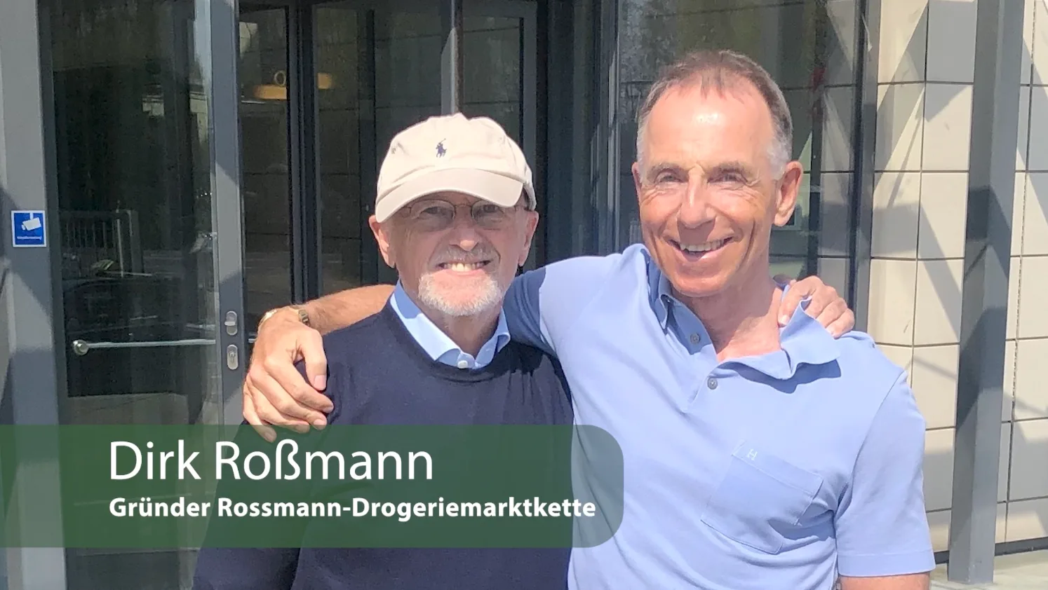 Master-Class Membership Finanzielle Freiheit von Rainer Zitelmann 5 Dirk Roßmann und ein weiterer Mann vor Gebäudeeingang, Gründer Rossmann-Drogeriemarkt