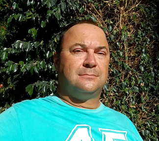 Porträtfoto von Mann vor grünem Efeu-Hintergrund, türkises T-Shirt