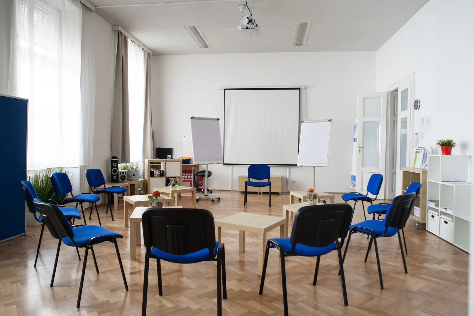 Moderner Seminarraum mit blauen Stühlen, Flipcharts und Präsentationsmaterial