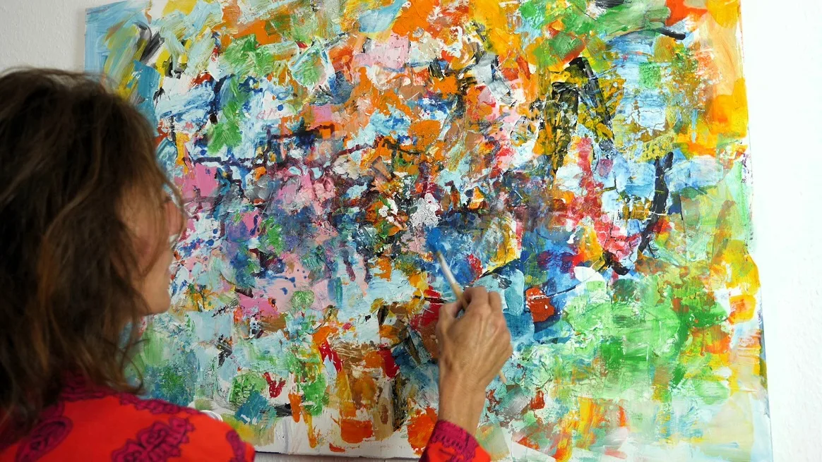 Hero-Banner mit Frau in rotem Shirt beim intuitiven Malen auf buntem abstraktem Kunstwerk