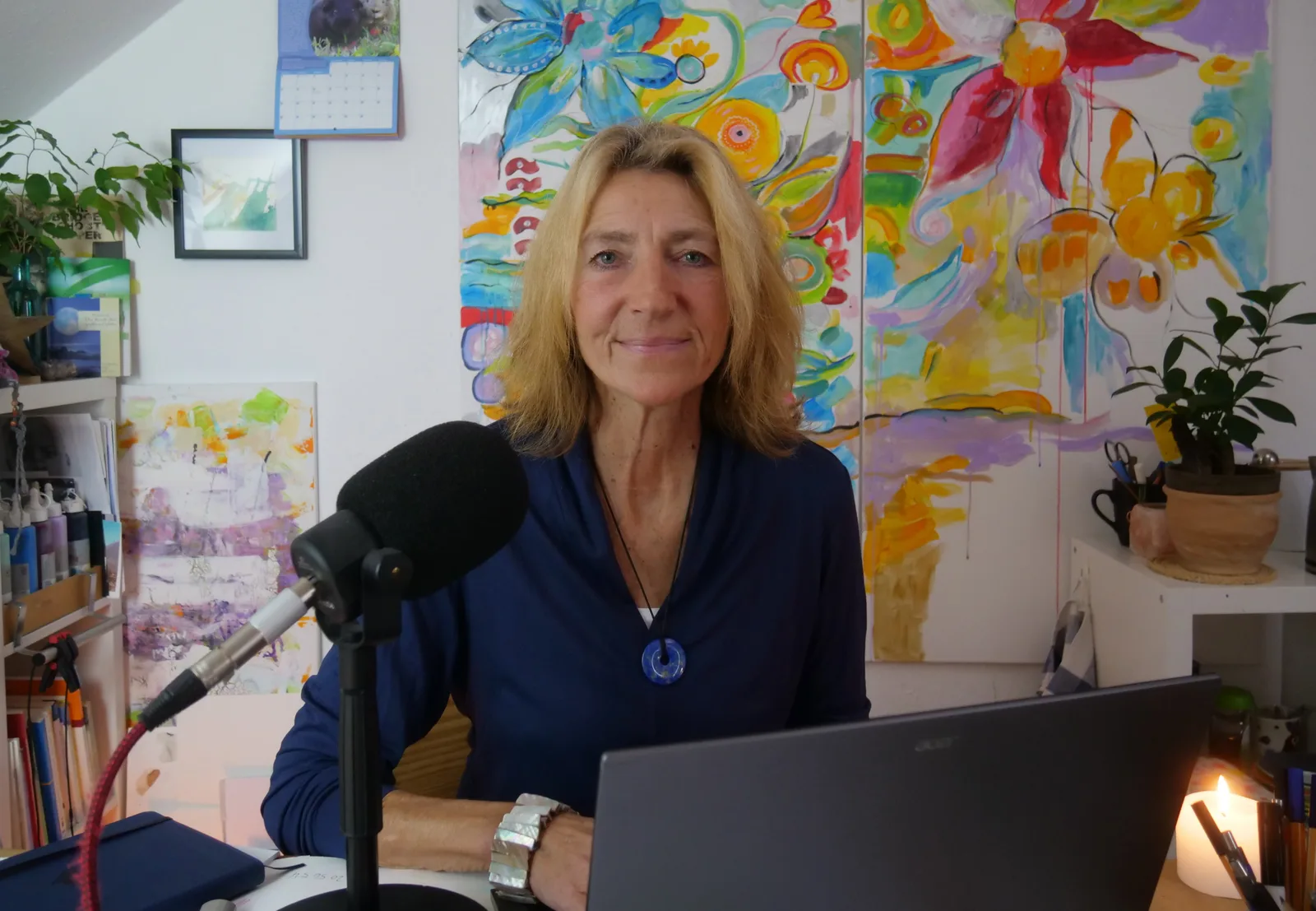 Portrait von Karin Henningsen, blonde Frau vor buntem abstraktem Kunstwerk mit Mikrofon