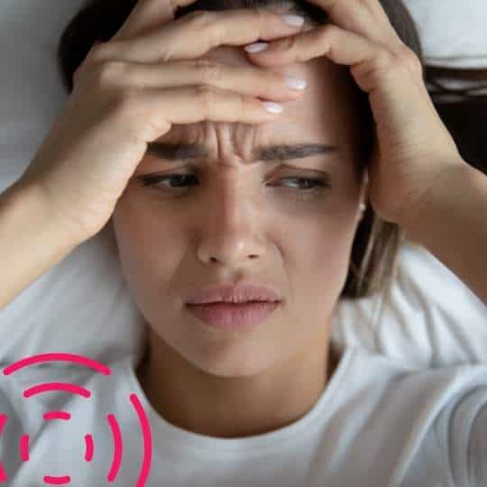 Erschöpfte Mutter mit Kopf in Händen, besorgte Gesichtszüge, dekorativ pinkfarbene Wellen