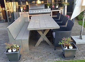 Gartentisch mit X-Gestell und schwarzen Stühlen auf Terrassenpflaster