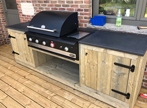 Fertiggestellter Außengrill aus Holz mit schwarzem Grilltop auf Holzterrasse