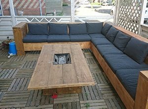 Großes L-förmiges Ecksofa aus Holz mit Kissen und Couchtisch auf Terrasse