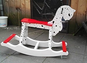 Weißes Schaukelpferd mit roten Akzenten und schwarzer Mähne