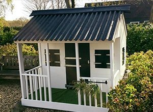 Weißes Gartenhaus mit schwarzem Dach und grünen Türen auf Rasen