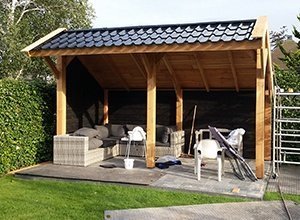 Überdachter Holzpavillon mit Seitenwänden und Grill auf Rasen