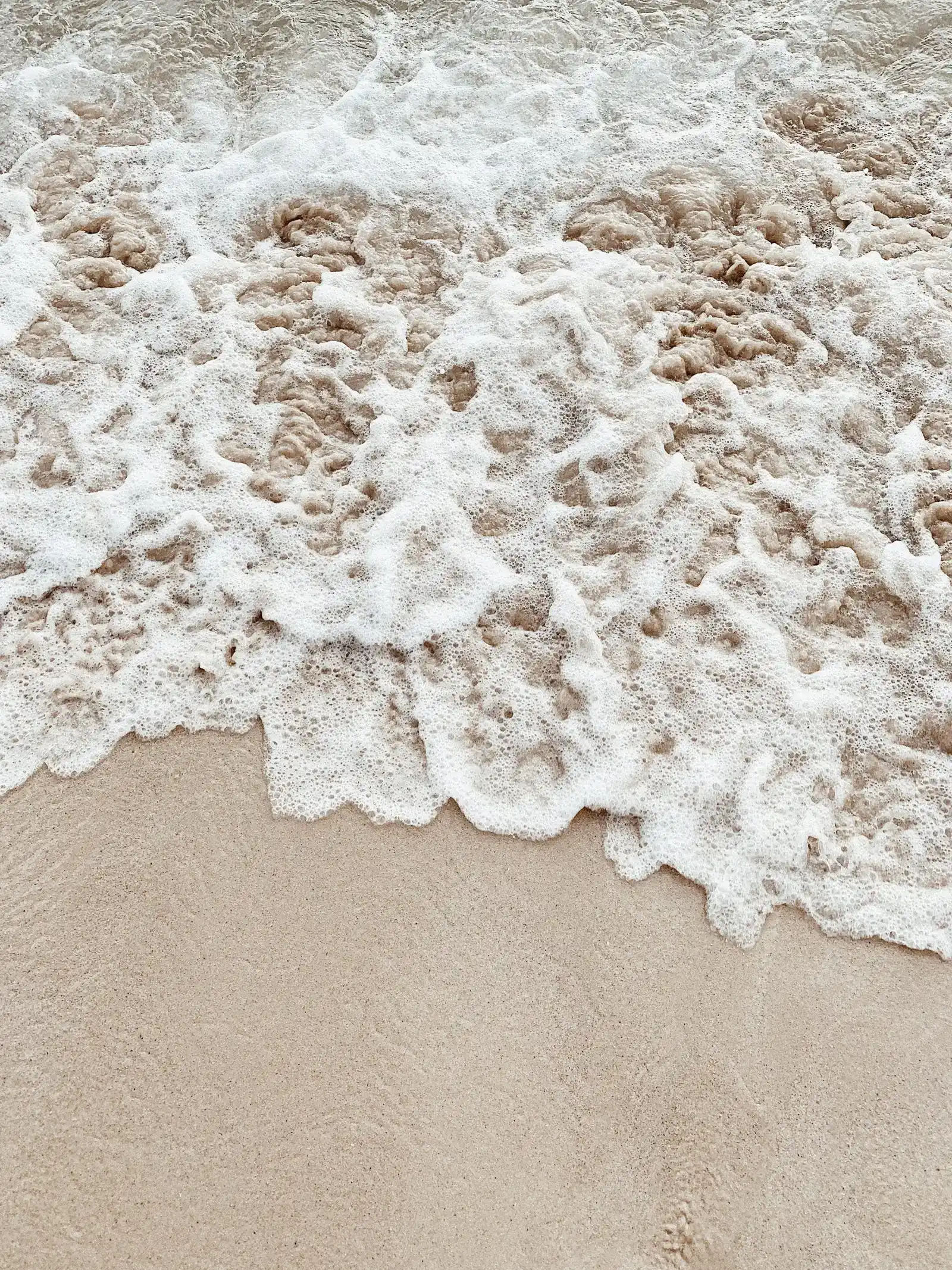 Nahaufnahme von Wellen und Schaum am Sandstrand