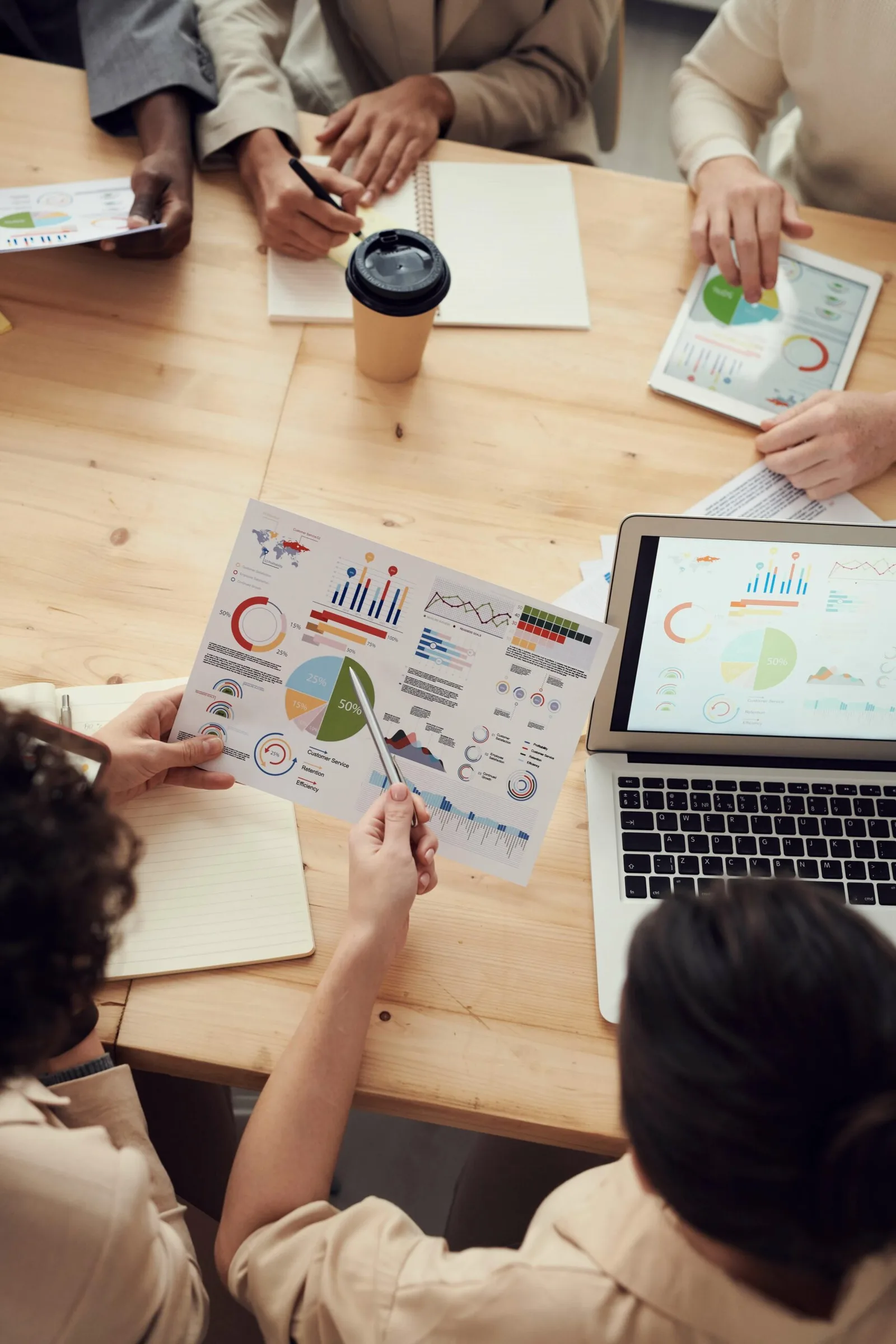 Menschen bei Tisch mit Kaffee, Tablet und Diagrammen analysieren Geschäftsdaten und Statistiken