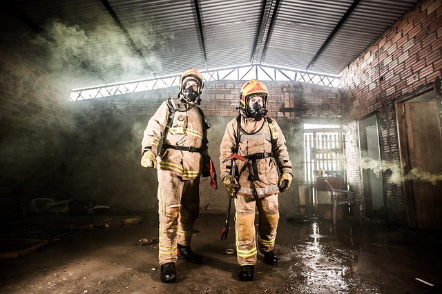 Zwei Feuerwehrmänner in Schutzausrüstung in verrauchter Trainingshalle