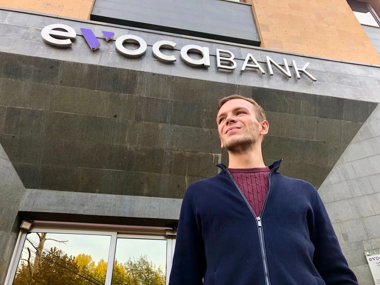 Mann vor Gebäude mit Evocabank-Schriftzug, blickt nach oben