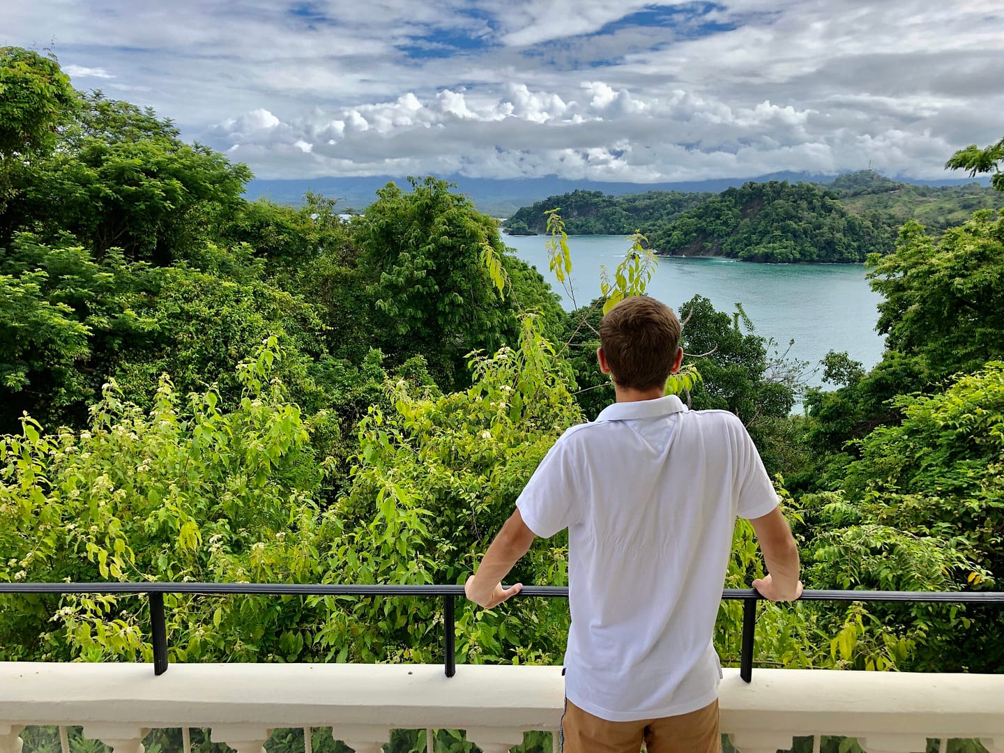 Mann in weißem Poloshirt an Balkon mit Dschungelblick auf Fluss in Costa Rica