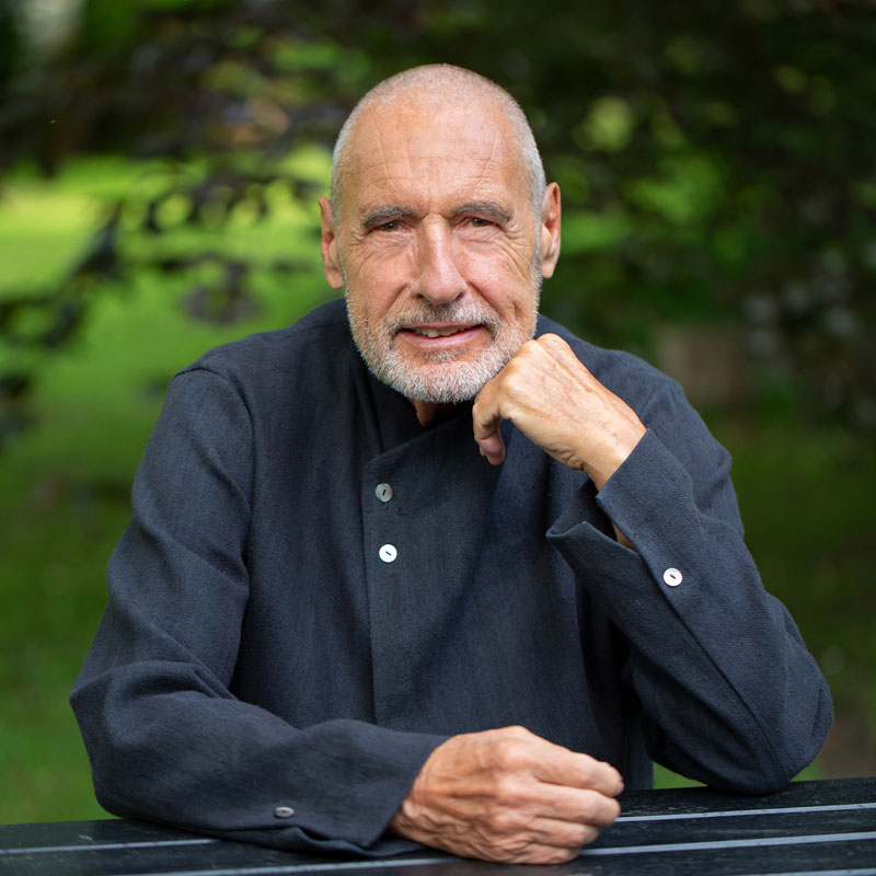Karl Gamper Nahportrait im grünen Garten mit gestütztem Arm