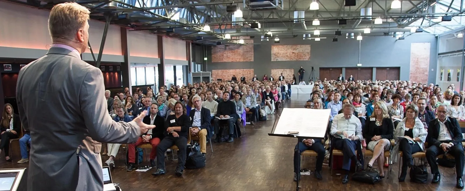 Raho Bornhorst präsentiert vor großer Menschenmenge in moderner Industriehalle