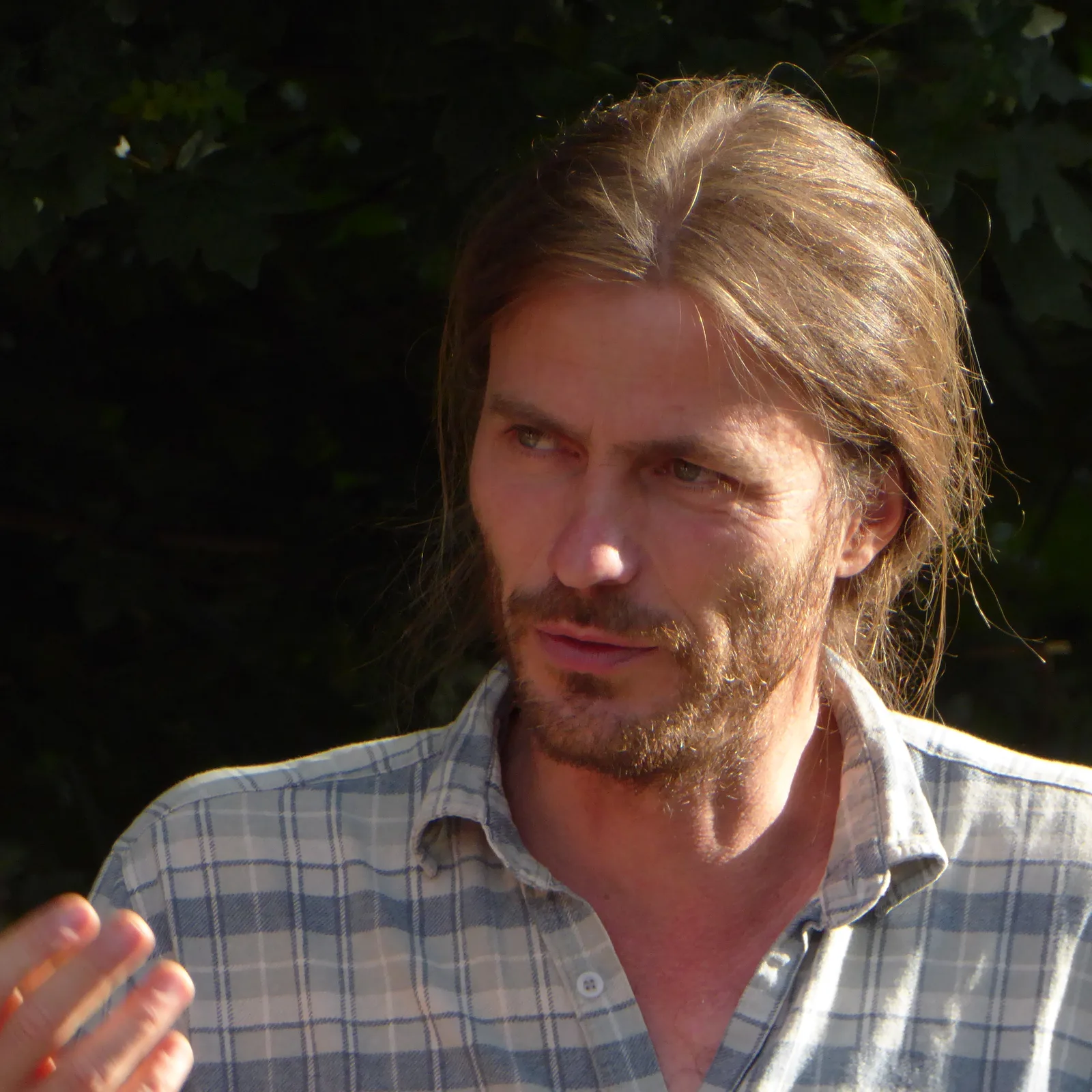 Thomas Meier mit langem Haar und Hemd in Nahaufnahme vor grünem Hintergrund