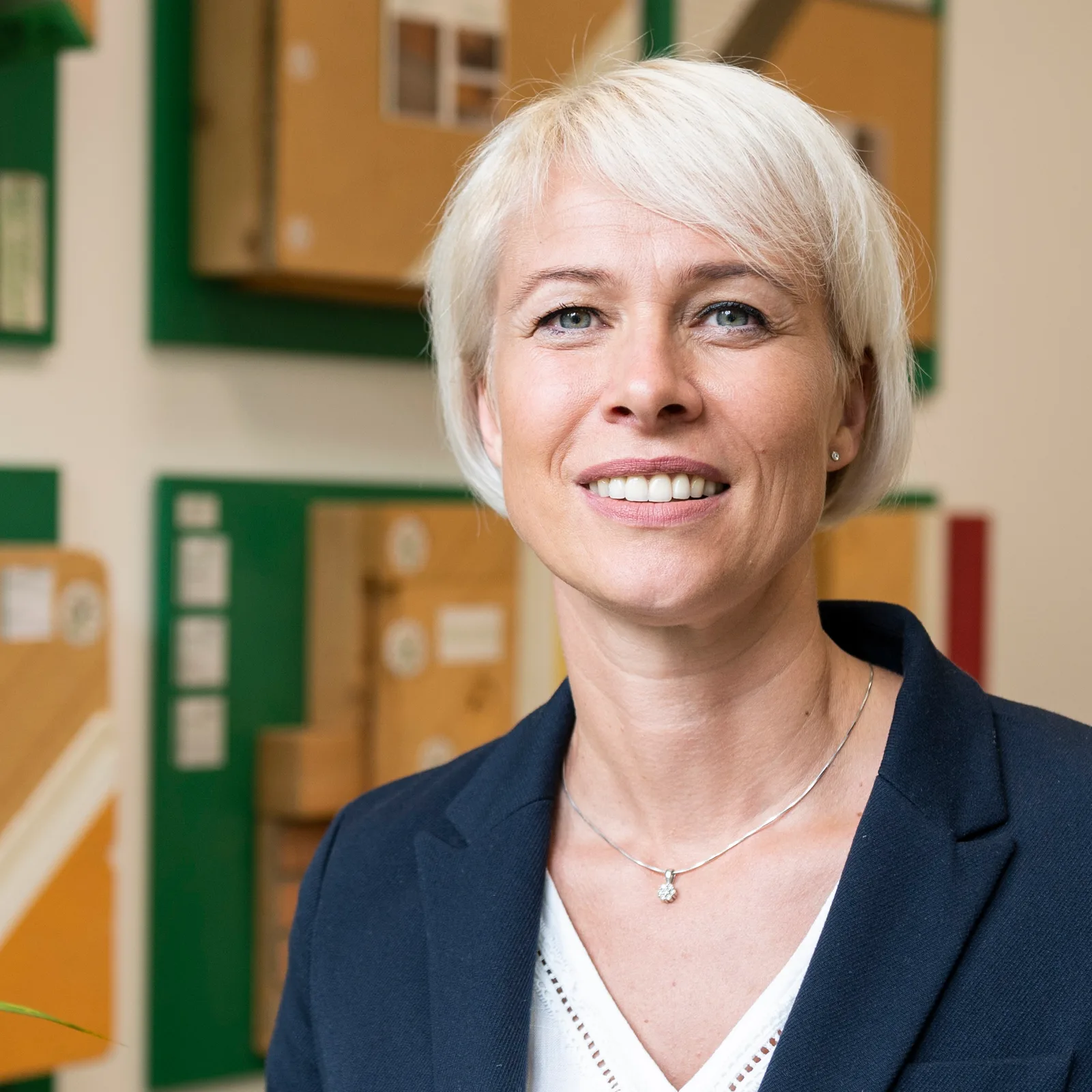 Anka Unger, Frau mit weißem Haar vor farbigen Elementen, professionelles Porträt