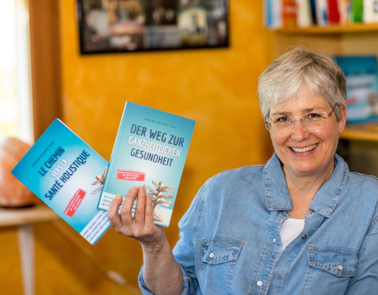 Gesundheitskompass – Gesundheitscoaching mit Analyse 4 Sabrine Callaert hält zwei Bücher: 'Le Chemin' und 'Der Weg zur ganzheitlichen Gesundheit'