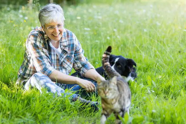 Gesundheitskompass – Gesundheitscoaching mit Analyse 3 Sabrine Callaert sitzt lächelnd im Gras mit schwarzweißem Hund