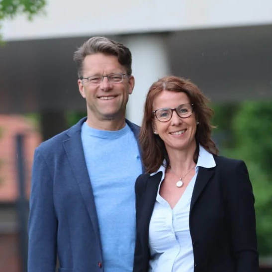 Paar-Porträt von Roland und Ute Jentschura vor unscharfem Hintergrund