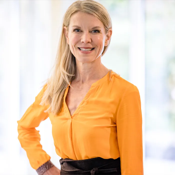 Porträt von Anja Wagner, Frau mit blondem Haar in orange Bluse