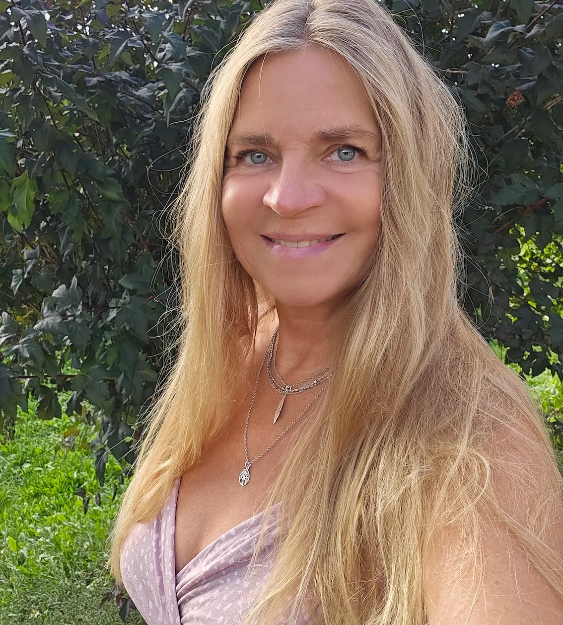 Porträt von Sylvia Vera Baschwitz, Frau mit blondem Haar vor Grünfläche