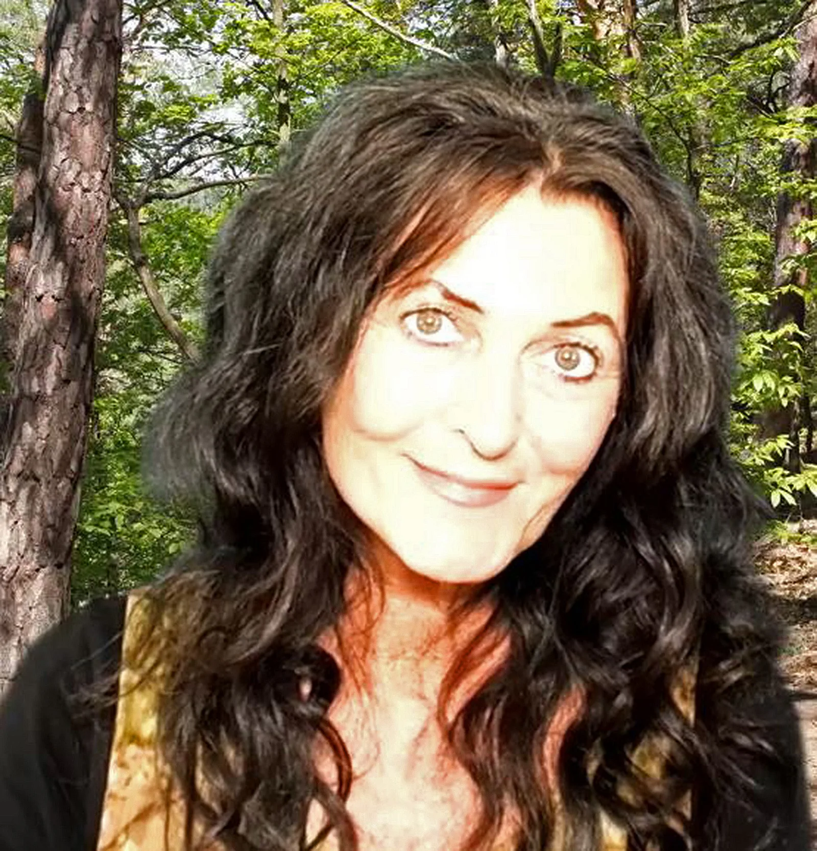 Britta Diana Petri, Frau mit schwarzen Haaren vor Waldkulisse in Nahaufnahme
